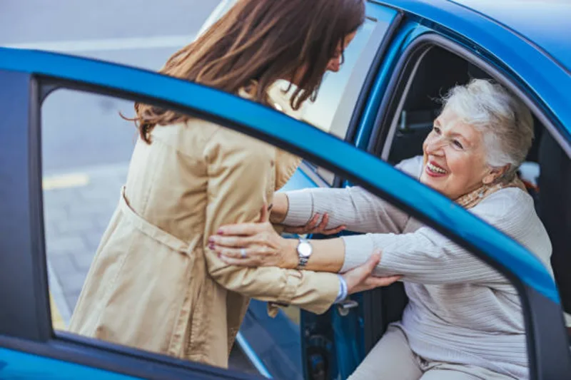 Caregiver helping elderly parent into car